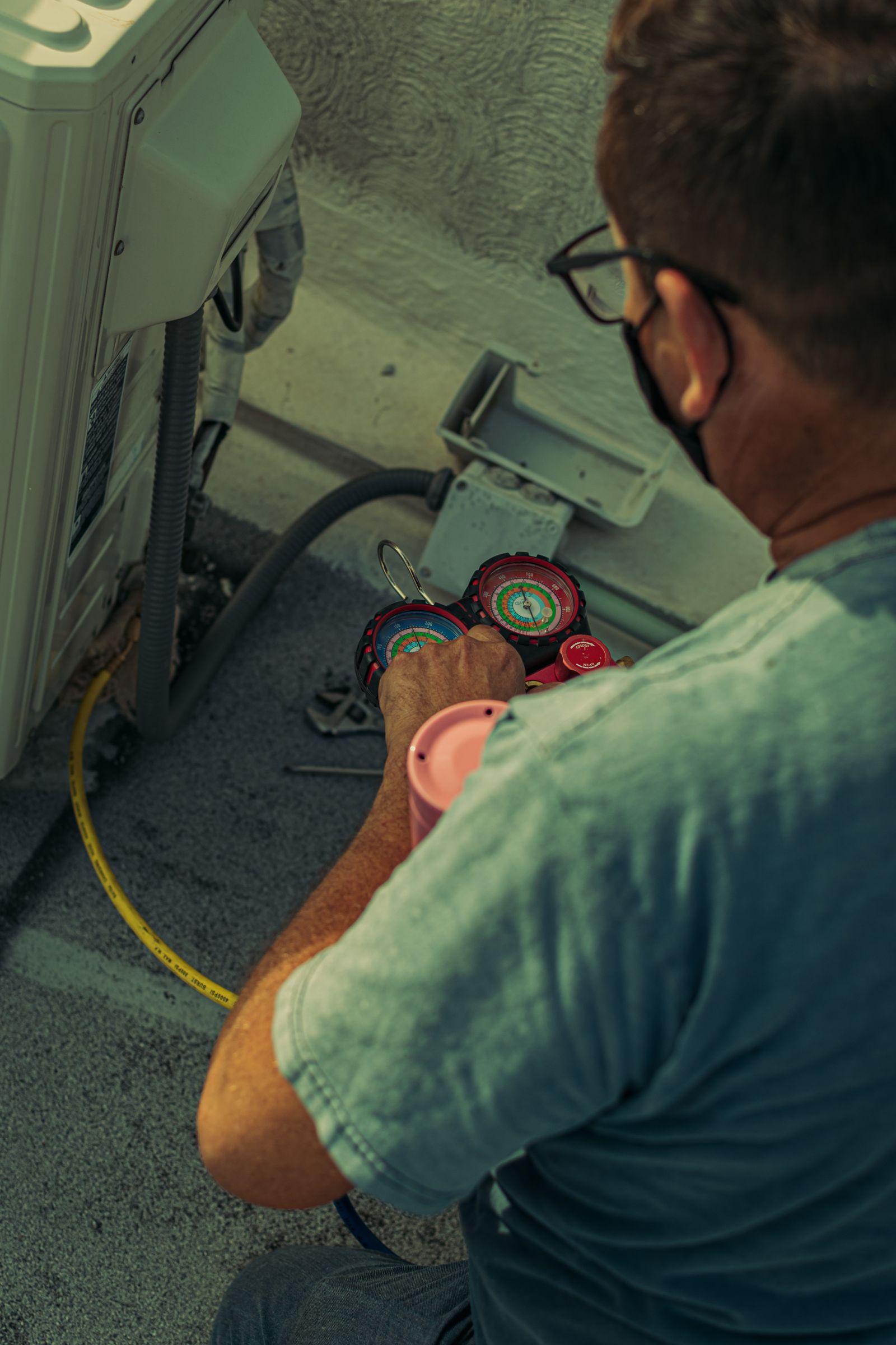 Technician checking refrigerant pressure gauges during HVAC maintenance