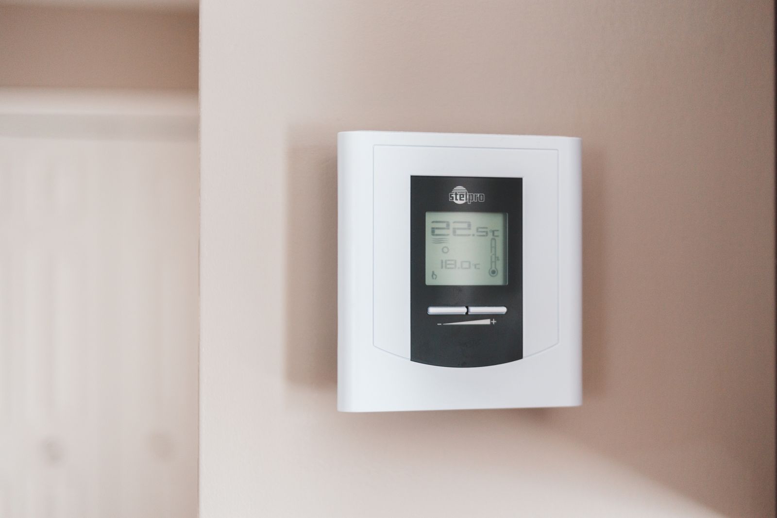 Digital thermostat mounted on a home wall displaying the temperature